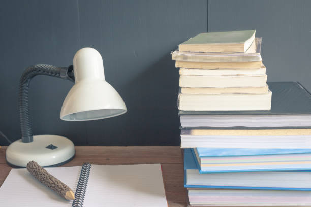 istock Workplace with reading lamp and books on old wooden table. vintage concept 1008439470