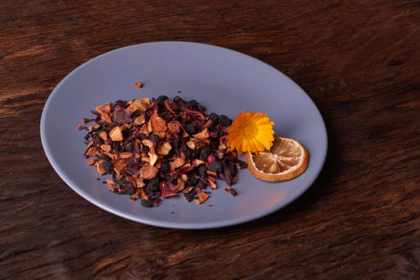 istock Black dry fruit tea leaves in blue plate on wooden table. Selective focus 1008455038