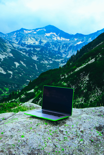 Laptop computer at the natural mountain background. Photo depicts notebook computer in the alpine heights. Freelance concept.