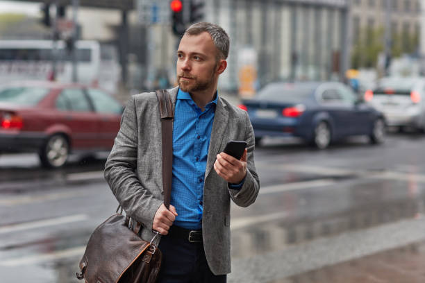 istock Businessman with bag and smart phone looking away 1008457682