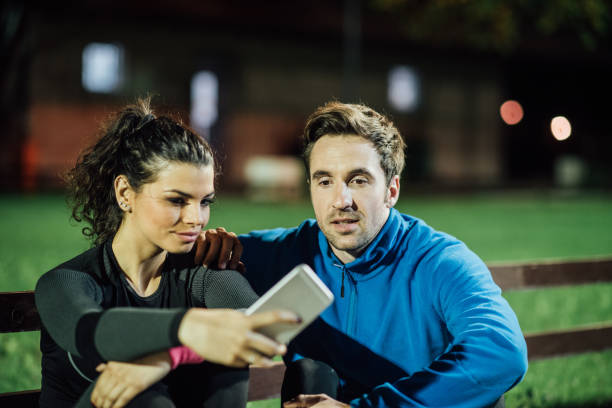 istock Athletic couple taking a selfie while sitting on the bench in the park 1008461156