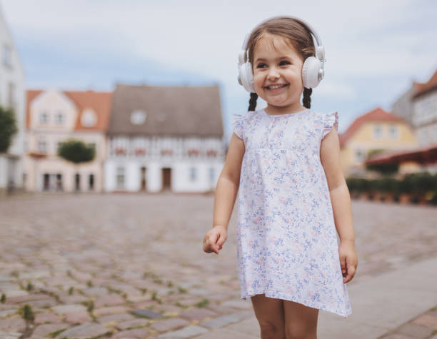 superbes filles bambin souriant, écouter de la musique sur le casque à l’extérieur - north sea audio photos et images de collection