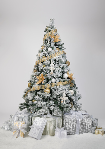 Beautiful decorated christmas tree in gold and white colors in front of a white background.