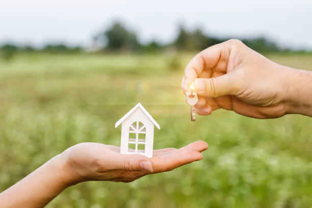 istock Hand with keys and a hand holding a model house . 1008498934