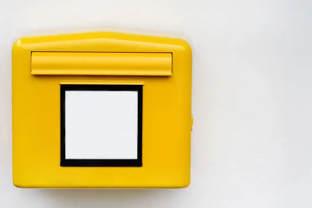 Yellow iron mailbox on white wall. Close-up photo of mail box with empty sign in Germany, Europe