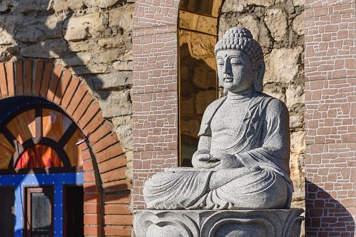 White stone statue of a Buddha on masonry background