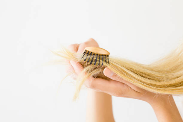 istock Woman's hand combing blonde hair on the light gray background. Hair problem and solution. Daily preparation for good looking. Women's issues. 1008543788