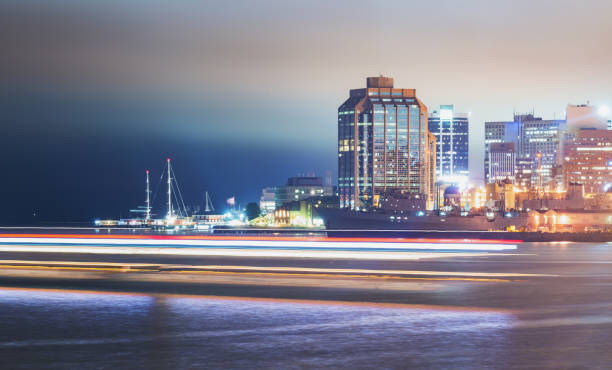 A tour boat passes in the foreground of the Halifax waterfront on a foggy night.  Long exposure.