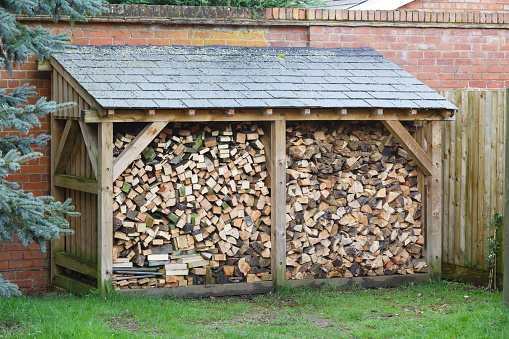 Large log store filled with firewood, timber construction with a slate roof