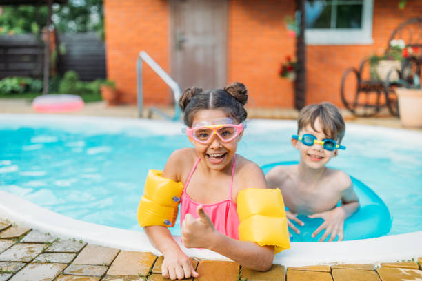 petits frères et sœurs, nager dans la piscine ensemble le jour de l’été - inflatable ring water wings swimming pool float photos et images de collection