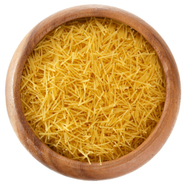 istock Curly pasta in a round wooden bowl isolated on white background, top view 1008570452