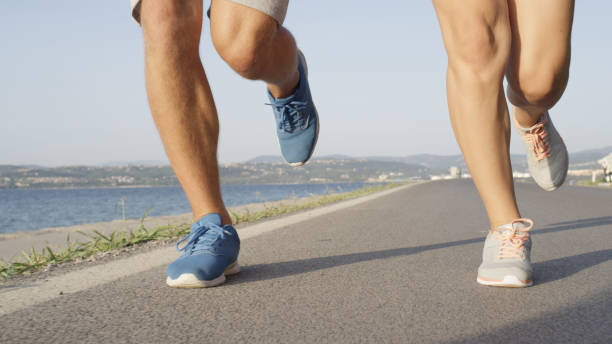 istock LOW ANGLE: Unrecognizable couple jogs down peaceful walkway near the ocean. 1008573236