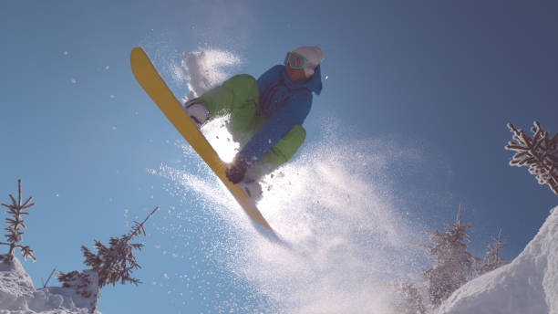 istock CLOSE UP: Pro snowboarder takes off and does a cool trick while covering the sun 1008573462