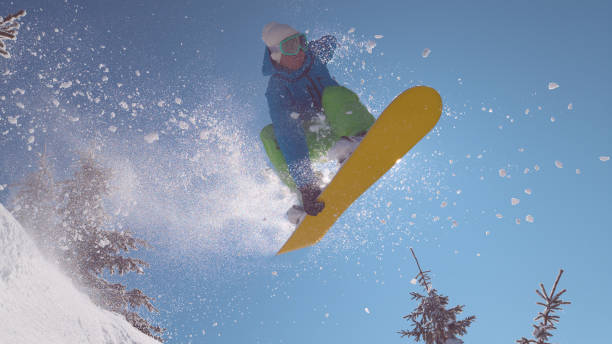 istock CLOSE UP: Thrilled snowboarder riding off piste in ski resort does awesome trick 1008573478