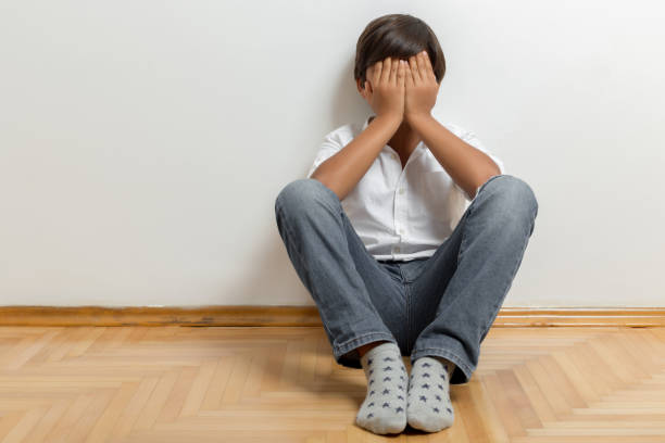 Unhappy boy sitting on floor