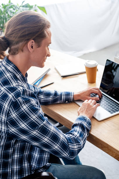 istock high angle view of man using laptop with blank screen at workplace 1008581136