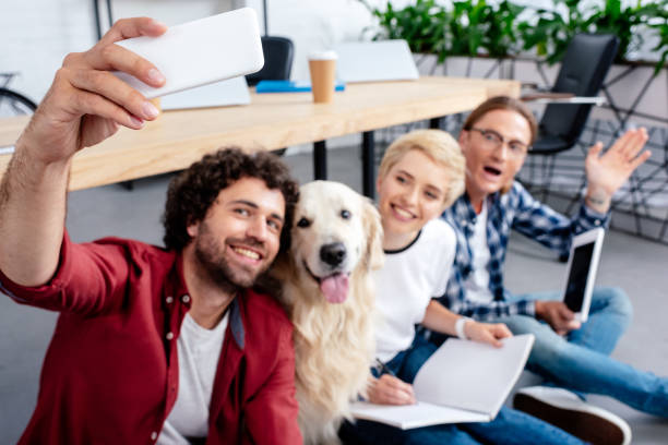 istock happy young people taking selfie with dog in office 1008599846