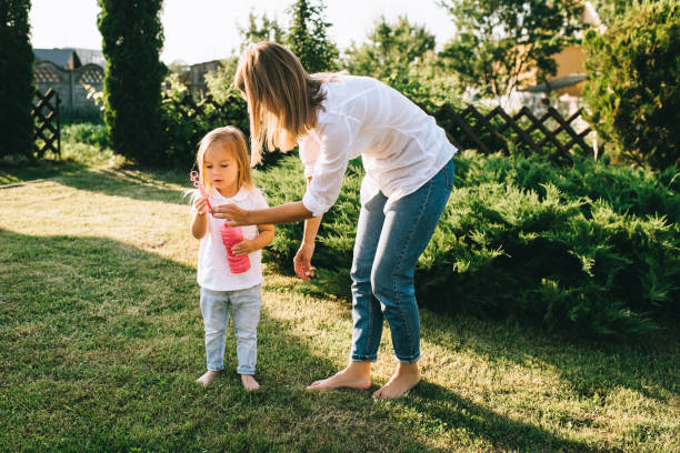 istock mother helping little daughter blowing soap bubbles on backyard 1008600644