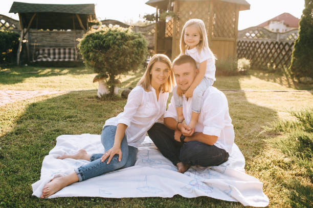 istock parents and little daughter resting on cloth on ground together on backyard 1008601054