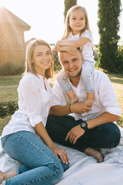 istock parents and little daughter resting on cloth on ground together on backyard 1008601116