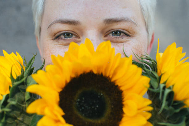 istock summer fun, blonde girl hiding behind sunflowers 1008620986