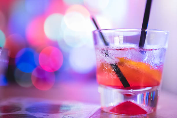 istock Cocktail glass with straw, on a table, with Christmas lights in the back. 1008655982