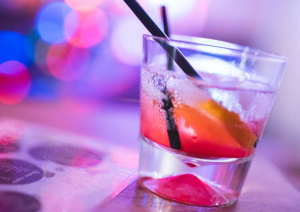 istock Cocktail glass with straw, on a table, with Christmas lights in the back. 1008657462