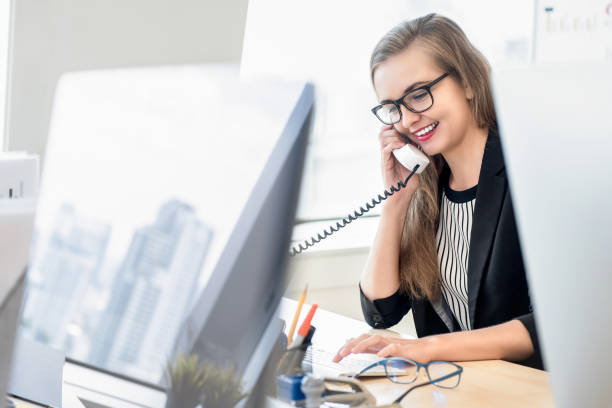 Businesswoman talking on the phone with customer at work Happy businesswoman as a customer care representative talking on the phone at work with her client in the office file clerk stock pictures, royalty-free photos & images