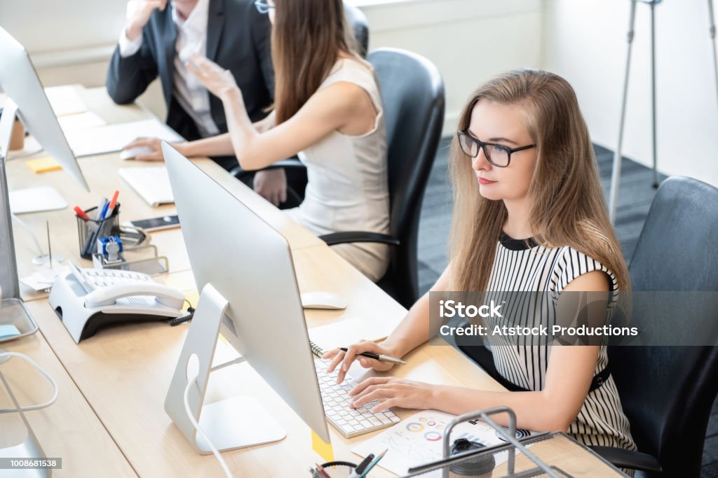 Businesswoman working on computer in the office Businesswoman white collar worker concentrating on working with desktop computer in the office Junior Level Stock Photo