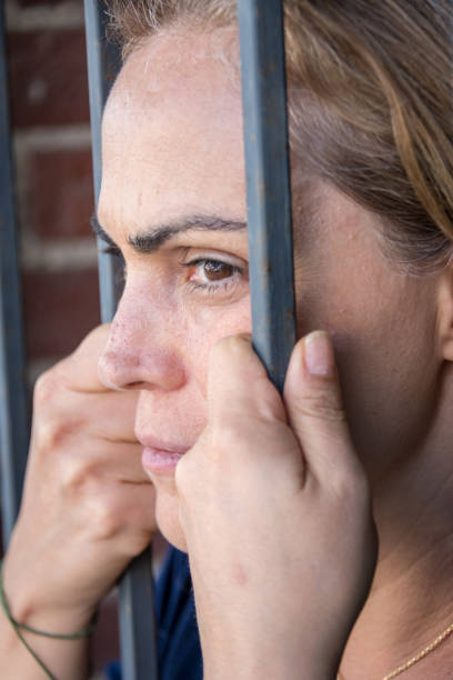 istock serious mature woman behind bars 1008700164