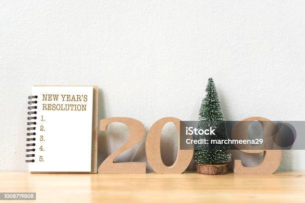 New Years Resolution On A Notebook And Wood Number 2019 With Christmas Tree On Wood Table And Copy Space Stock Photo - Download Image Now