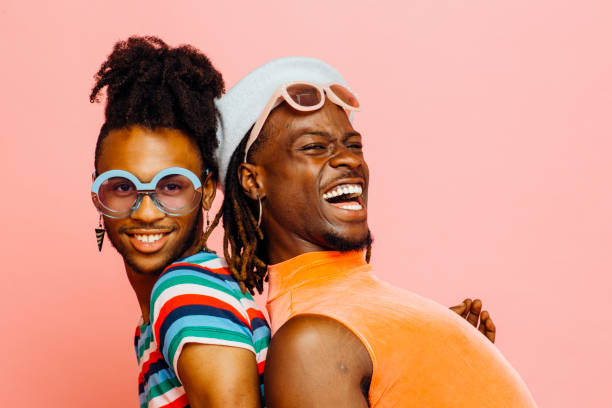 Enjoying summer love/ Portrait of a gay couple with big smiles Enjoying summer love/ Portrait of a gay couple with big smiles, isolated on pink background homosexual stock pictures, royalty-free photos & images