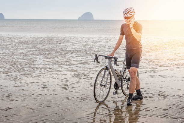 istock Young asian cyclist man ride  bicycle  the beach at the sunset 1008765430