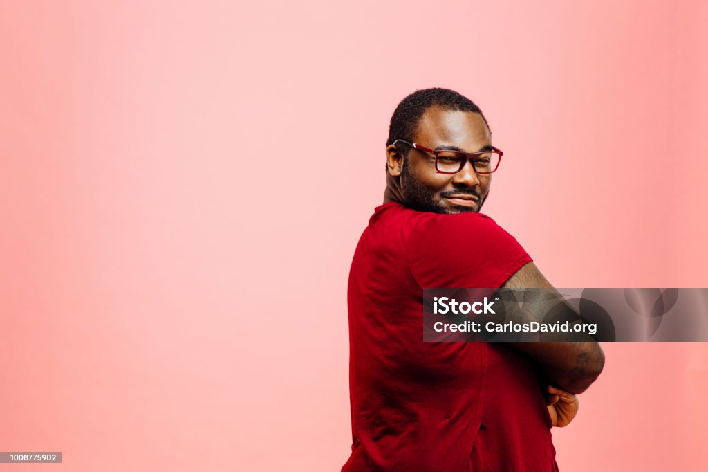 Ritratto di un uomo plus size in camicia rossa e occhiali che guardano indietro la fotocamera - Foto stock royalty-free di Uomini