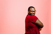 Portrait of a plus size man in red shirt and glasses looking back at camera