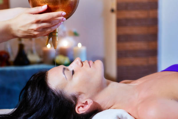 woman enjoying a ayurveda oil massage treatment in a spa - ayurveda massaging aromatherapy chakra imagens e fotografias de stock