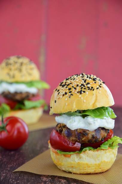 istock Sesame burger bun with lentil patty and veggie on red background 1008797028