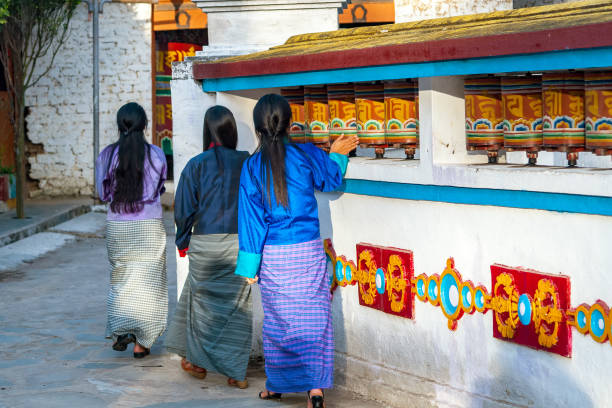 lokalen bhutanischen frauen drehen gebetsmühlen - bhutan - bhutan himalayas wheel vibrant color stock-fotos und bilder