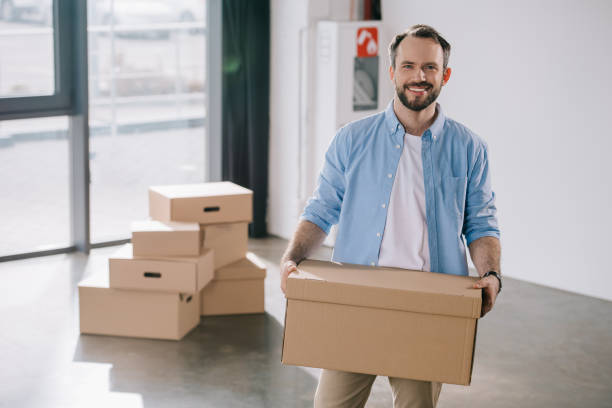 istock happy bearded businessman holding cardboard box and smiling at camera while moving in new office 1008844840