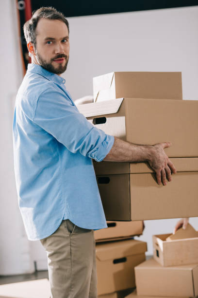 istock bearded businessman holding cardboard boxes and looking at camera while moving in new office 1008844900