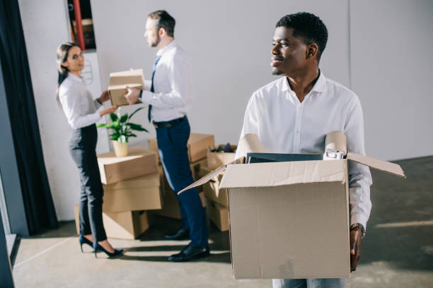 istock smiling african american businessman holding cardboard box while relocating with colleagues in new office 1008845200