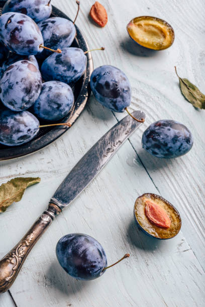 istock Plums with leaves and knife over wooden surface 1008851208