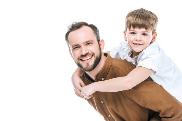 happy father piggybacking little son and smiling at camera isolated on white - boyhood imagens e fotografias de stock