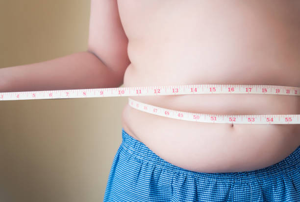 Fat boy with overweight checking Fat boy with overweight checking out his weight isolated on white background af_istocker stock pictures, royalty-free photos & images