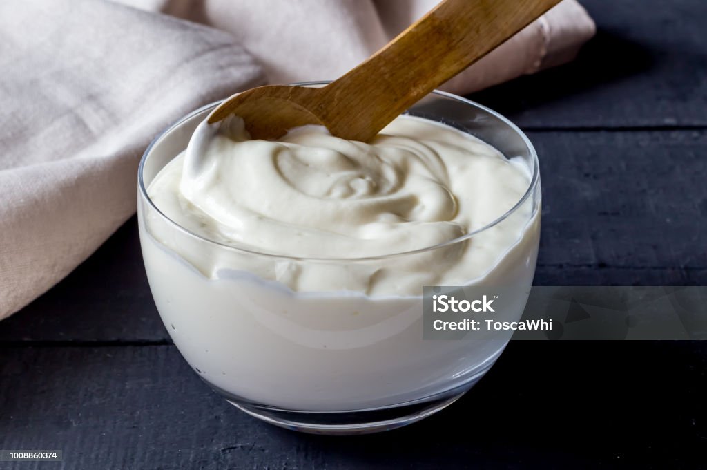 Yogurt in bowl on rustic black table - Photo of plain natural organic yoghurt close up. Yogurt Stock Photo