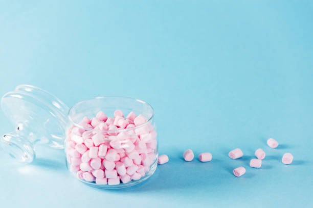 istock Creative minimal still life on pastel blue colored background. Glass bowl with cute pink marshmallows. Copyspace 1008885060