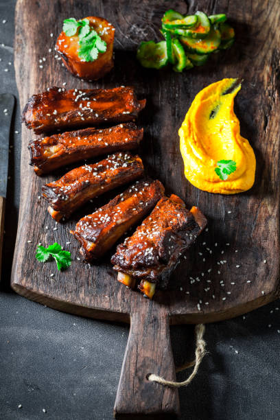 istock Delicious roasted ribs with vegetables and potato on old plank 1008885942