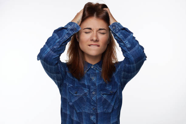istock American female closing eyes with worried expression, bites lip, 1008902930