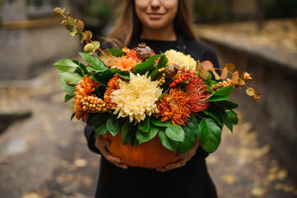 mujer sosteniendo una calabaza con flores de otoño - fall bouqet fotografías e imágenes de stock