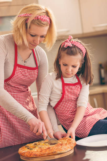 istock Mother and daughter cutting pizza 1008909546